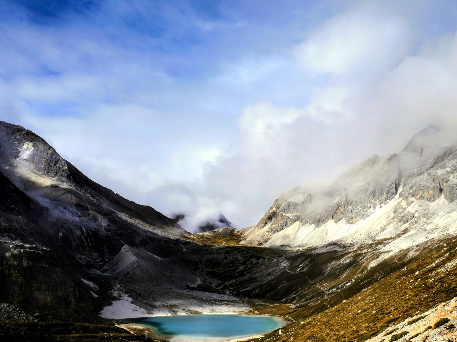 稻城亚丁牛奶海：青蓝色湖水环抱于高山之间，雪峰与云层静静相望。